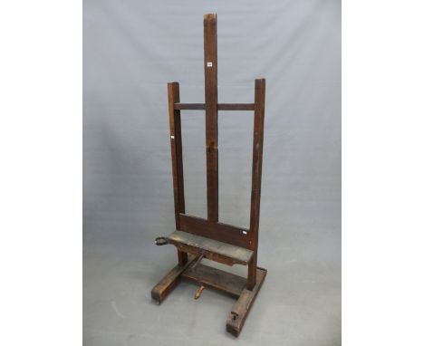 A VINTAGE OAK EASEL, THE PICTURE RESTING CRANKING UP AND DOWN ON A WOODEN SCREW AND WITH FOLD OUT DISH BENEATH ONE SIDE, THE 