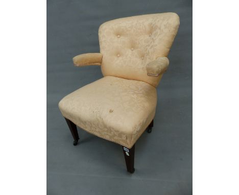 AN EDWARDIAN MAHOGANY BUTTON BACKED ARMCHAIR, THE ROUNDED ARMS CANTILEVERED FROM THE BACK, THE STUFFED SEAT ON TAPERING SQUAR