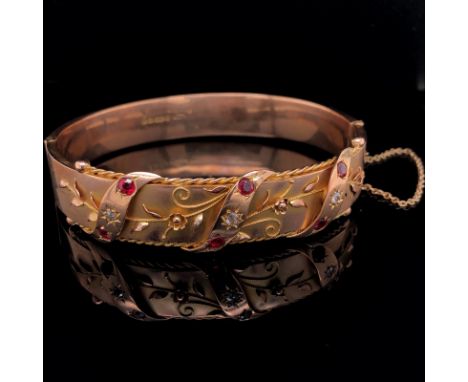 AN EDWARDIAN ANTIQUE 9ct OLD GOLD RUBY AND DIAMOND BANGLE, DATED 1910 FOR BIRMINGHAM. THE FRONT WITH WIRE WORK AND APPLIED 3-