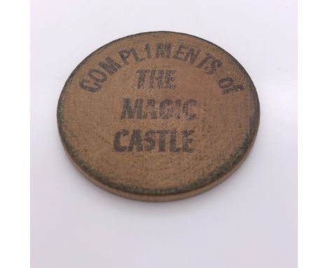 A WOODEN ROUNDEL INSCRIBED IN BLACK ON ONE SIDE COMPLIMENTS OF THE MAGIC CASTLE AND ON THE OTHER WITH TUIT.   Dia. 4cms.