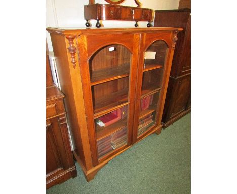 A mahogany bookcase with two glazed doors with arched tops enclosing three adjustable shelves, the side fronts with short pil