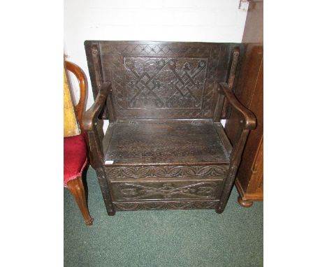 20th century dark oak monk's bench of dowel fixed construction, with carved diapering to back panel and stylized carved folia