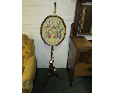 Victorian fire screen lately converted to an electric standard lamp, the oval panel with applied brass moulding, the brass co