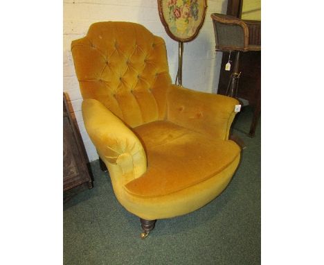 Edwardian gentleman's armchair in gold coloured button-back upholstery with turned front legs and brass castors (height 97cm)