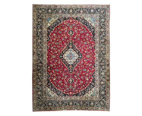 Persian Kashan crimson ground carpet, the central pole medallion decorated with flower heads, surrounded by trailing leafy br