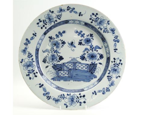 18th century English Delft charger, decorated in underglaze blue with a fence and peony, within a floral and geometric border