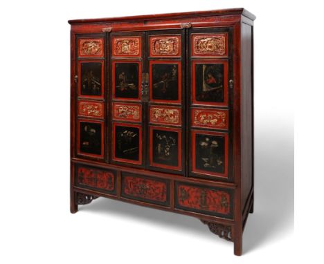 19th century Chinese red and black lacquered hardwood cabinet fitted with four panelled doors, the frieze decorated with scro