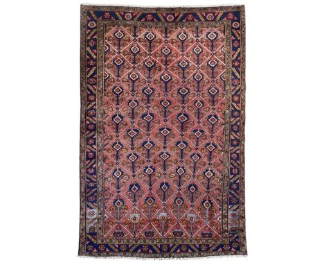 Persian Ardakan crimson ground rug, the field divided by lattice and decorated with stylised tree of life motifs, the border 