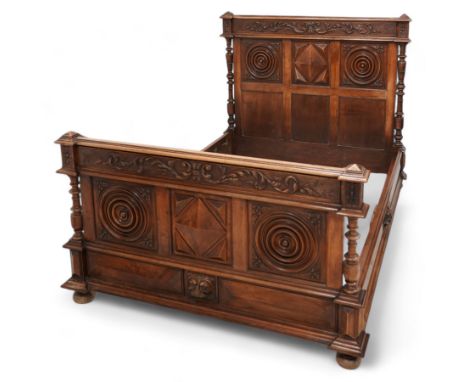 Late 19th century French walnut double bedstead, the panelled headboard with curling foliage carved frieze over concentric tu