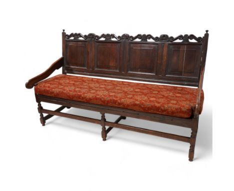 Early 18th century oak hall bench or settle, the cresting rail carved with S-scrolls and crown motifs, over a quadruple panel