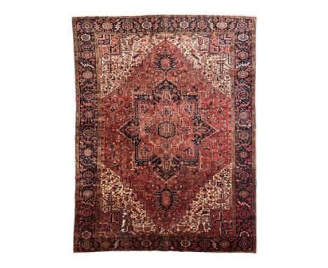 Persian Heriz red ground carpet, large stylised pole medallion surrounded by Pitrak motifs, indigo ground border decorated wi