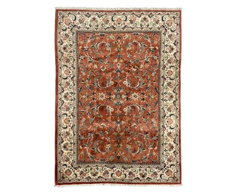 Persian Kashan peach ground rug, the field decorated with swirling leafy branches and stylised plant motifs, ivory ground bor