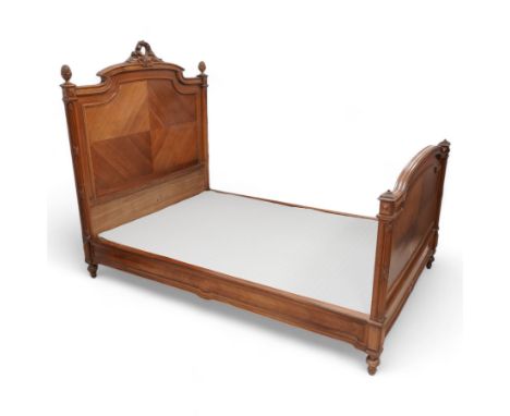 20th century French walnut 4' 6'' double bedstead, the headboard with flower head wreath pediment flanked by carved pineapple