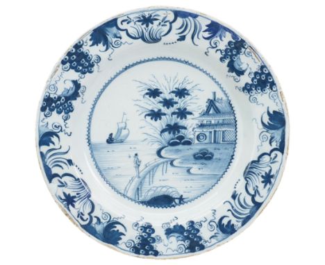 18th century English Delft charger, painted in blue with a Chinese scene with a figure in a boat, another figure crossing a b