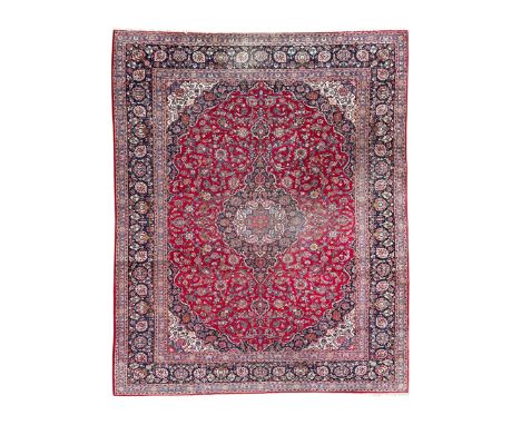 Large Persian Kashan crimson ground carpet, central floral medallion surrounded by swirling leafy branches and palmettes, enc