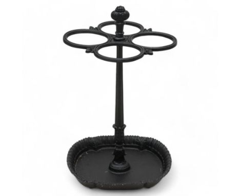 Victorian cast iron umbrella stick stand, fluted stem with four holders decorated with acanthus leaf mouldings, over foliage 