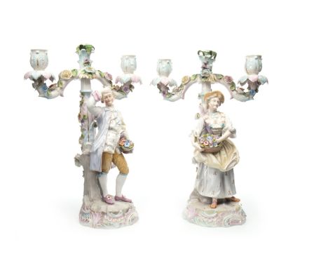 PAIR OF GERMAN PORCELAIN FIGURAL CANDELABRA, modelled as a lady and a gentleman holding flower baskets, on circular bases, th
