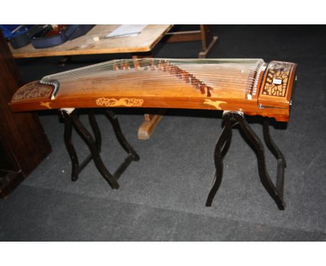 A CHINESE GUZHENG, plucked 21 string instrument with bird and foliage fretwork panels to either end and standing on two trest