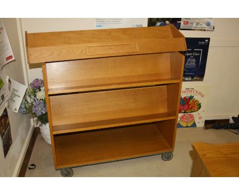 AN OAK VENEERED DOUBLE SIDED ROLLING BOOK STAND AND AN OAK BOOK SLIDE, stand measures 91x43x92cm, slide 107x26x16cm