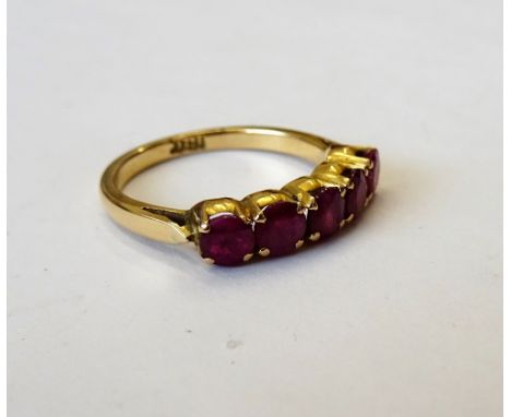 A gold and ruby five stone ring, claw set with a row of circular cut rubies, detailed indistinctly 18 CT, ring size O.