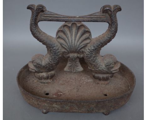 A Victorian cast iron boot scraper, the foot plate raised on twin mythological fish on an oval dished base and four feet, 36c