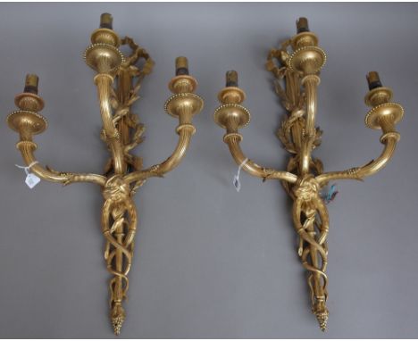 A set of four Louis XVI style gilt bronze three light wall appliques, late 19th century, each with ribbon tied surmount and f