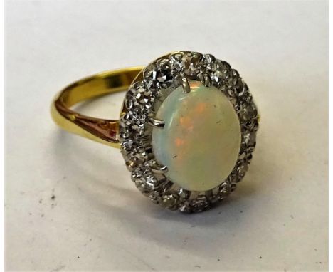 A gold, opal and diamond oval cluster ring, claw set with the oval opal in a surround of circular cut diamonds, detailed 18 C