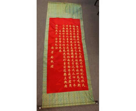 A Chinese hanging embroidered scroll, with gilt calligraphy on a red ground, 152cm. by 68cm. 