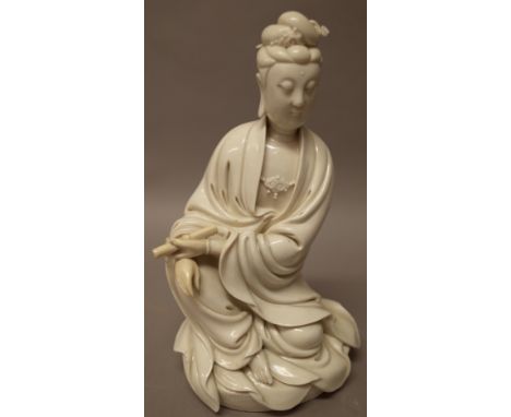 A Chinese blanc de chine figure of Guanyin, modelled seated holding a scroll in her left hand, the oval base with incised her