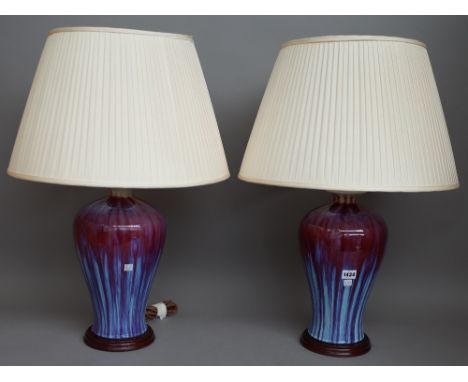 A pair of modern Chinese style flambe pottery table lamps, each of baluster form on a wooden base with cream pleated shades, 