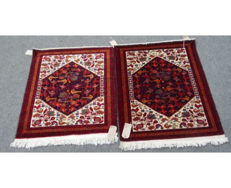 Two similar Baluchistan mats, each with an indigo field and ivory surround, filled with birds, a vase of flowers to each corn