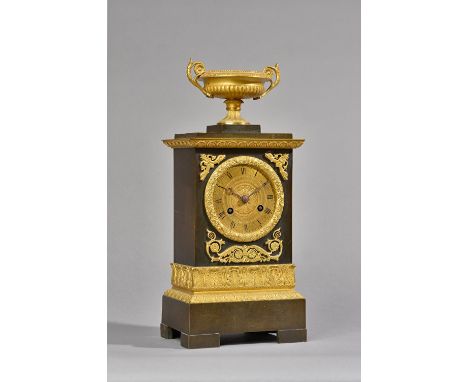 A French Empire style ormolu mounted bronze mantel clock, C.1860, with an urn surmount over a rectangular body enclosing a tw