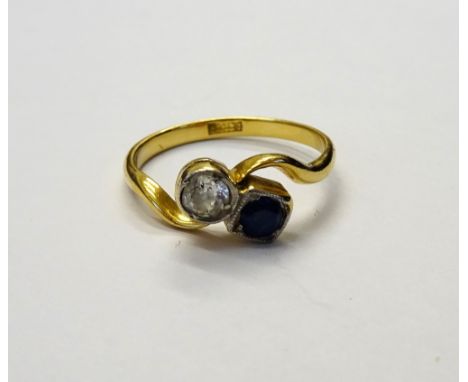 A gold, diamond and sapphire two stone ring, mounted with a cushion shaped diamond and with a circular cut sapphire in a twis