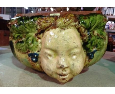 A Continental pottery wall fountain basin, late 19th/20th century, moulded in high relief with the face of a youth flanked by