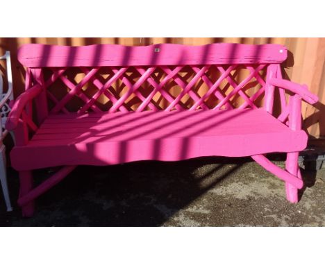 A neon pink painted hardwood garden bench of naturalistic form, 178cm wide. 