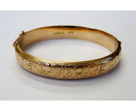 A 9ct gold oval hinged bangle, the front with floral, foliate and scroll engraved decoration, on a snap clasp, Chester 1918, 