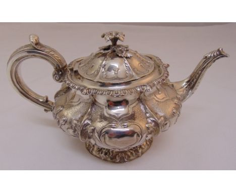 A George IV hallmarked silver teapot, compressed circular form, the lobed body chased with leaves and flowers, leaf capped sc