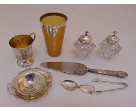 A quantity of silver to include a horn beaker with silver mounts, a cup, a tea strainer on stand, a childs spoon, a cake slic