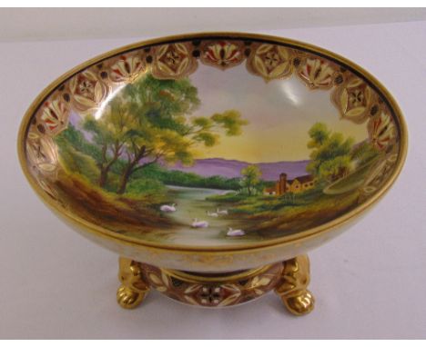 Noritake comport decorated with a landscape and gilded border on removable raised circular base with gilded paw feet