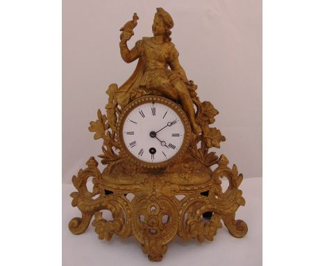 A French gilded metal late 19th century mantle clock with white enamel dial and Roman numerals surmounted by a figurine holdi