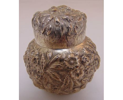 A white metal tea caddy with domed pull off cover profusely chased with leaves and flowers, approx total weight 133g