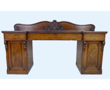 An early Victorian mahogany sideboard server, with scroll carved back, three frieze drawers, and twin pedestal cupboards with