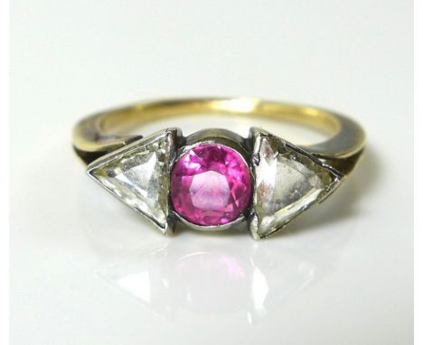 An Art Deco ring with central oval old cut ruby of approximately 4.7 by 3.9mm flanked by two unusual old cut triangular diamo