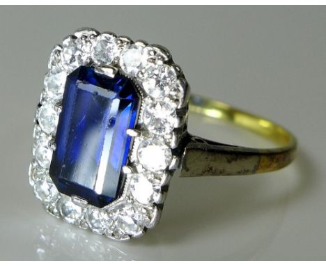 A sapphire and diamond dress ring, the large emerald cut central sapphire encircled by fourteen diamond brilliants, approx 0.