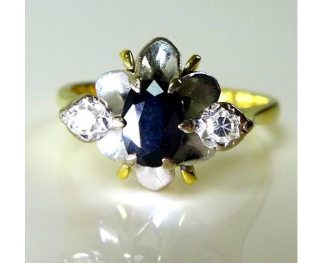 An 18ct gold, diamond and sapphire dress ring, the oval cut central sapphire with two illusion set diamonds to either side an