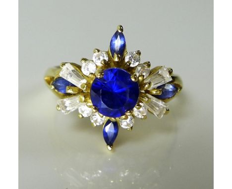 An 18ct gold, sapphire and white stone dress ring, the raised starburst setting with central sapphire of approximately 5.7 by