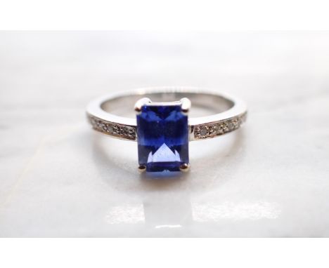 A  Sapphire and Diamond Ring corner claw-set step-cut sapphire, 1.53cts, between pavé-set brilliant-cut diamonds to shoulders