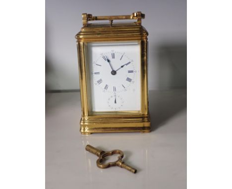 A brass repeating Alarm Carriage Clock with white enamel dial, Roman numerals and alarm subsidiary dial, coil striking moveme