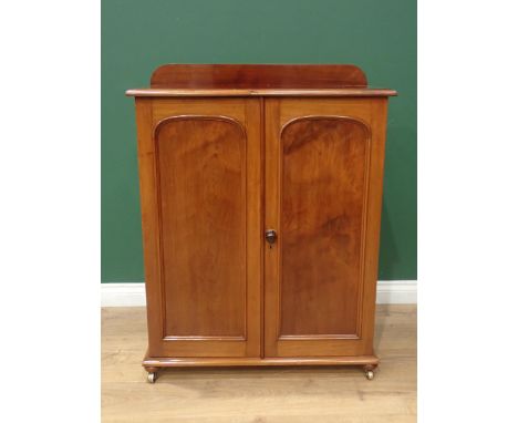 A Victorian walnut Cupboard fitted pair of arched panel doors enclosing drawer and adjustable shelves mounted on brass caster