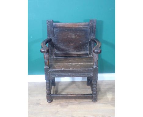 A 17th Century and later oak Armchair with plain panelled back, shaped arms, solid seat, on bobbin-turned front legs 